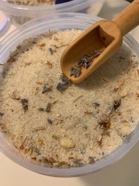 a bowl of lavender sand with a wooden spoon